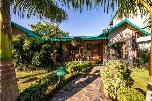 a house with a palm tree in front of it at Corbett Nirvana Resort in Amgarhi