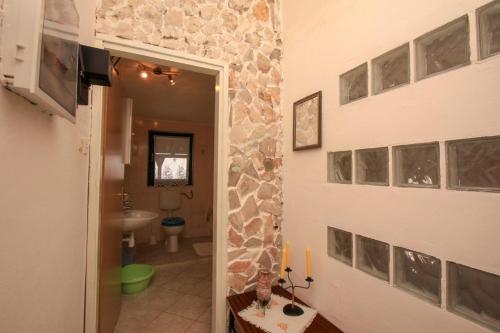 a hallway to a bathroom with a stone wall at Apartment Breza in Sućuraj