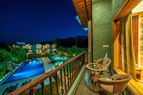 a balcony with a view of a swimming pool at night at Corbett Nirvana Resort in Amgarhi