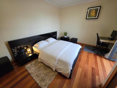 a bedroom with a large white bed and a desk at Quintinha do Álvaro - Holiday house in Santana