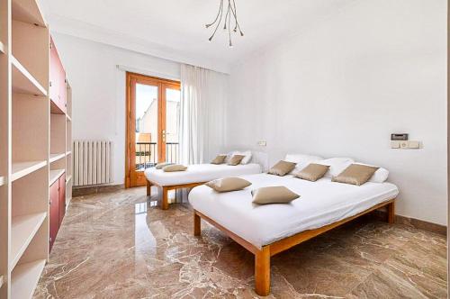 a white bedroom with two beds in it at Can Maro in Santa Margalida