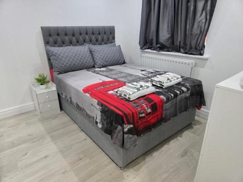 a bedroom with a bed with a black and red comforter at Luxury One Bedroom En-suite with Free Parking in Harrow Weald