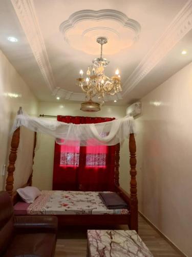 a bedroom with a bed with a chandelier at Venusia Villa in Darou Rhamane