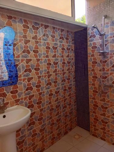 a bathroom with a sink and a stone wall at Venusia Villa in Darou Rhamane