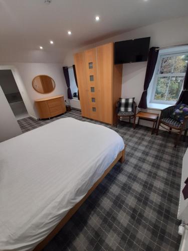 a bedroom with a large bed and a living room at Adderley House B&B in Pitlochry