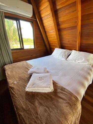 a bed in a room with two towels on it at LIMMAT Chalés- Presidente Juscelino, MA in Morros