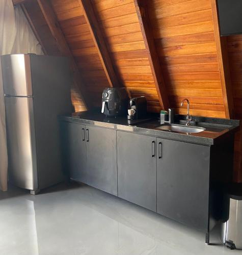 a kitchen with a stainless steel refrigerator and a sink at LIMMAT Chalés- Presidente Juscelino, MA in Morros