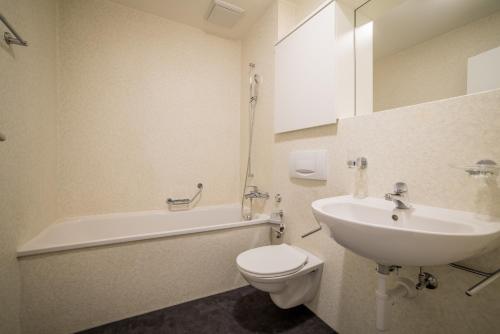 a bathroom with a sink and a toilet and a bath tub at Apartment Harderstrasse in Interlaken