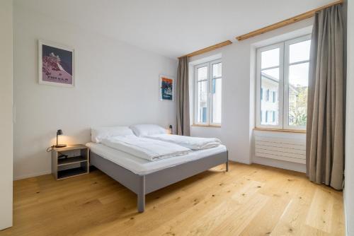 a white bedroom with a bed and a window at Apartment Harderstrasse in Interlaken