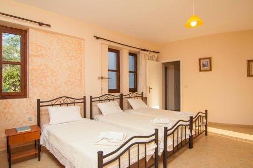 two beds in a room with two windows at Sarris Villa in Áyios Mámas