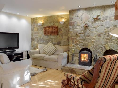 a living room with a stone wall with a fireplace at Alices Cottage in Stepaside