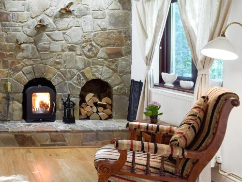 a stone fireplace in a living room with a chair at Alices Cottage in Stepaside