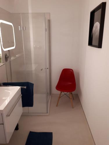 a red chair in a bathroom with a shower at Bergblick Kampenwand in Aschau im Chiemgau