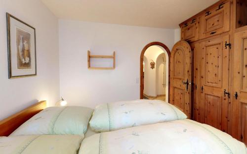 a bedroom with two beds and a wooden cabinet at Champagna in Celerina