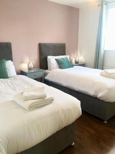 a bedroom with two beds with towels on them at The Orchid-Central Beeston-Private Apartment-SmartTV-Free Wi-Fi-Tram-Parking in Nottingham