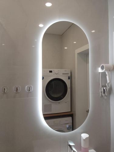a mirror in a bathroom with a washing machine at WOODSPACE Apartment in Shchūchīnsk