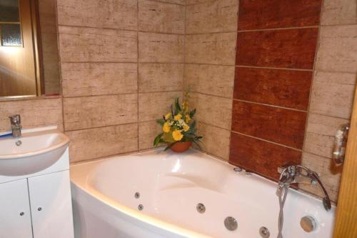 a bathroom with a bath tub with a sink and a flower at Komfortowy Apartament na wyłączność 2 Sypialnie Blisko Centrum in Gorlice