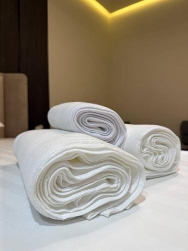 three white towels stacked on top of a bed at Fidji Hotel in Yerevan
