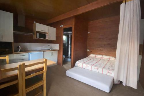 a small bedroom with a bed and a kitchen at Camping Playa Canelas in Portonovo