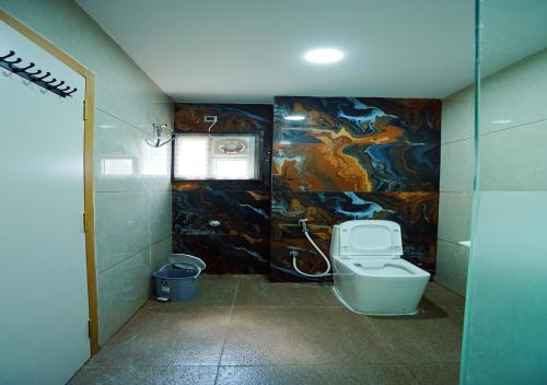 a bathroom with a toilet and a painting on the wall at Avenue A boutique hotel in Vijayawāda