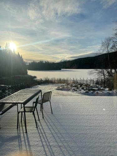 a table and two chairs sitting on a snow covered deck at Architect-Designed Cabin By Lake With Sauna in Homle