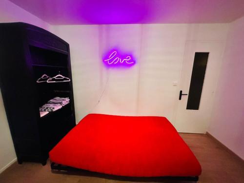 a room with a red bed and a neon sign at petit studio de bourgogne in Saint-Albain