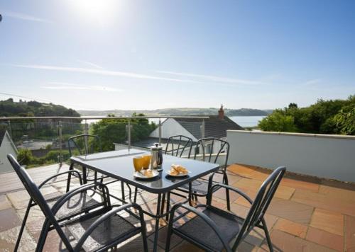 a table and chairs on a balcony with a view at Lloret, Contemporary Retreat with Hot Tub, Waterside and Castle Views, Dog friendly in Laugharne