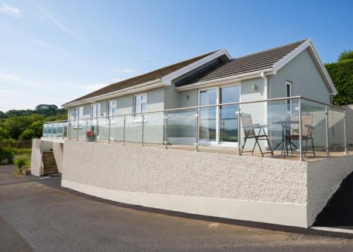 a house with a balcony with a table on it at Lloret, Contemporary Retreat with Hot Tub, Waterside and Castle Views, Dog friendly in Laugharne