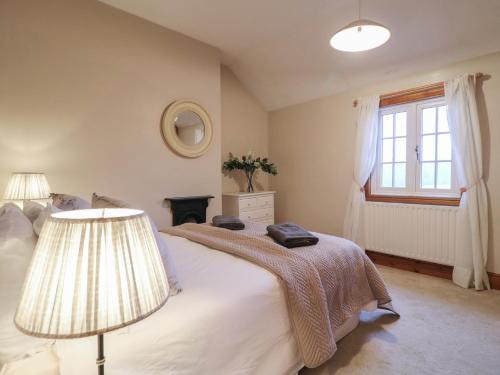 a bedroom with a bed with a lamp and a window at Little Launde Cottage in Leicester