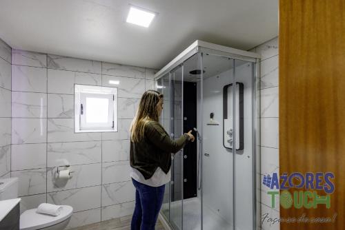 a woman standing in a shower in a bathroom at Sunset Pool House in Feteira