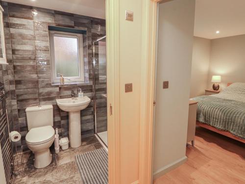 a bathroom with a toilet and a sink and a bed at The Nook in Wigton