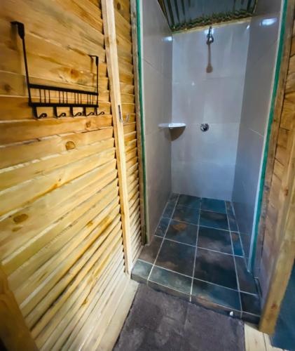 a bathroom with a shower stall and a tiled floor at Proteahill Guesthouse in Drummond