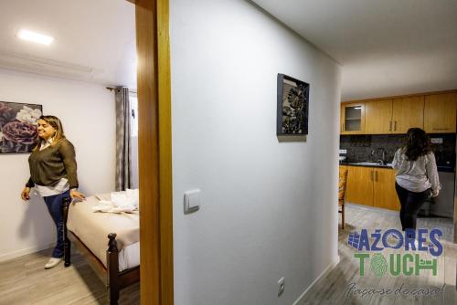 a woman standing in a room with a bed at Sunset Pool House T1 in Feteira