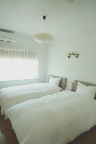 two white beds in a room with a window at Aioi house in Tsubetsu