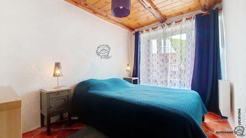 a bedroom with a blue bed and a window at La Ferrandaise in Chambon-sur-Lac