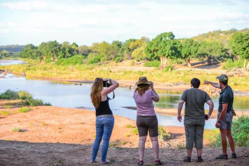 a group of people taking pictures of a river at Baluleni Safari Lodge in Grietjie Nature Reserve