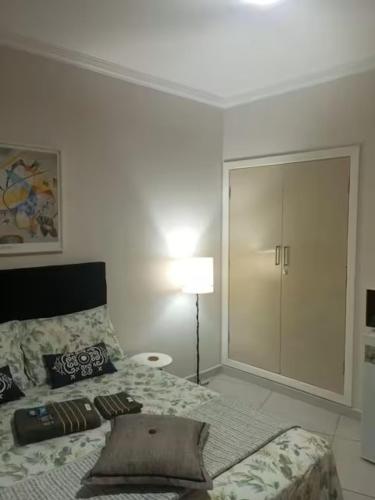 a white room with a bed and a lamp at Studio 215 Campinas SP in Campinas