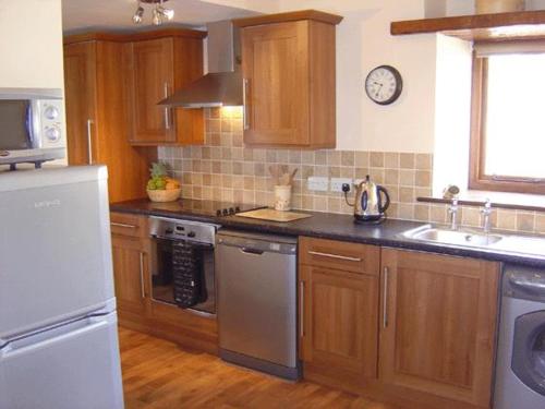a kitchen with wooden cabinets and stainless steel appliances at Oak Tree Cottage in Kirkbymoorside