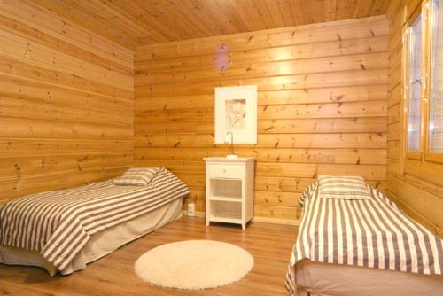 a bedroom with two beds in a wooden room at Himospeili in Jämsä