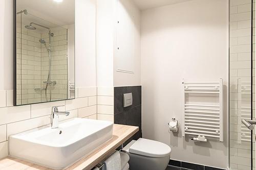 a white bathroom with a sink and a toilet at sylc. Apartmenthotel – Serviced Apartments in Hamburg