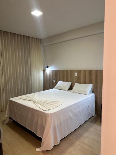 a bedroom with a large bed with white sheets at Hotel Oscar Gold Janaúba in Janaúba