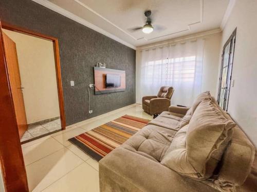 a living room with a couch and a tv at Casa espaçosa com ar em todos os quartos in Ourinhos