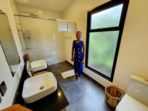 a woman standing in a bathroom with a window at MaraRiver TreeHouse in Musiara Campsite