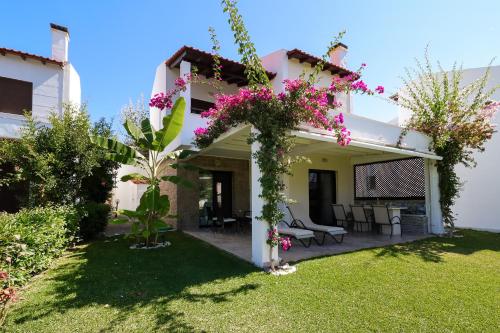 a view of a house with flowers in the yard at Sandra Villa Nea Skioni several steps from the sea in Nea Skioni