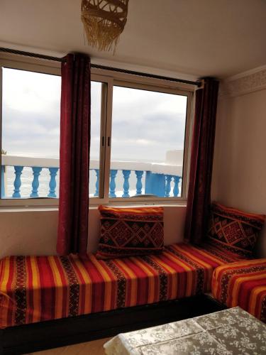 a room with two beds and two windows at Taghazout Beachside Haven Ocean View Apartment in Taghazout