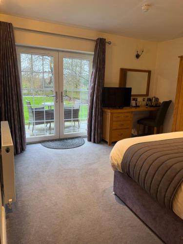 a bedroom with a bed and a desk and sliding glass doors at Charnock Farm in Leyland