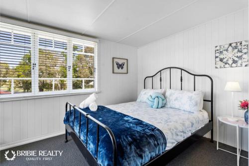 a bedroom with a bed with blue sheets and a window at BELLA ABODE AND POOL 4 Bedroom Entertainer in Bongaree