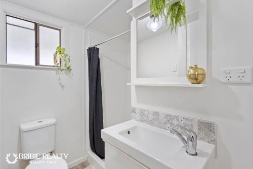 a white bathroom with a sink and a mirror at BELLA ABODE AND POOL 4 Bedroom Entertainer in Bongaree