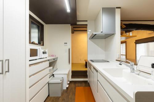 a kitchen with white cabinets and a sink and a microwave at Arai アライ in Takayama