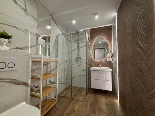 a bathroom with a shower and a sink and a mirror at Pokoje Gościnne MAGNAS in Poronin
